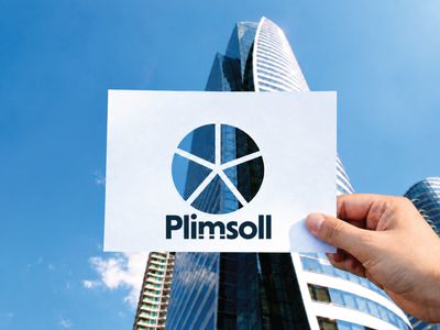 Hand holding a Plimsoll card with a cut-out pie chart divided into five segments, revealing parts of the same office building behind each segment.